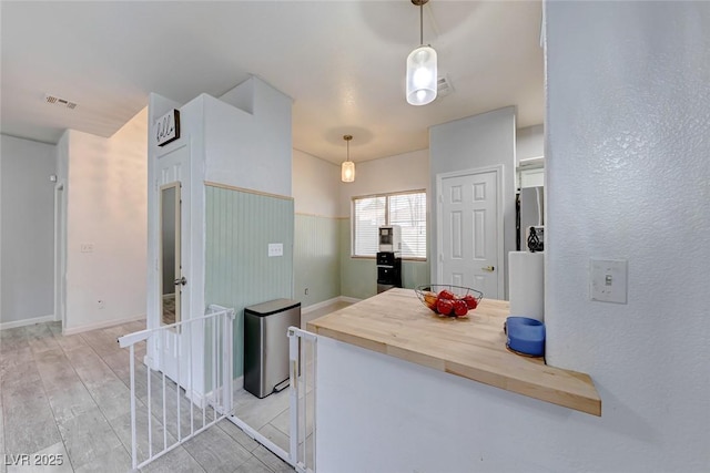 kitchen featuring wooden counters, pendant lighting, light hardwood / wood-style flooring, and stainless steel fridge