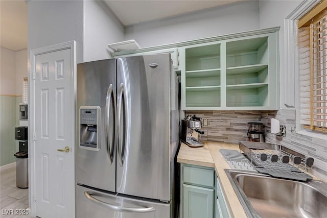 kitchen with butcher block counters, green cabinetry, sink, tasteful backsplash, and stainless steel fridge