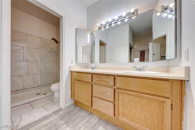 bathroom with tiled shower, vanity, and toilet