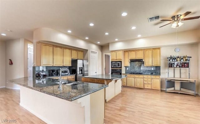 kitchen with a center island, black appliances, dark stone counters, ceiling fan, and sink