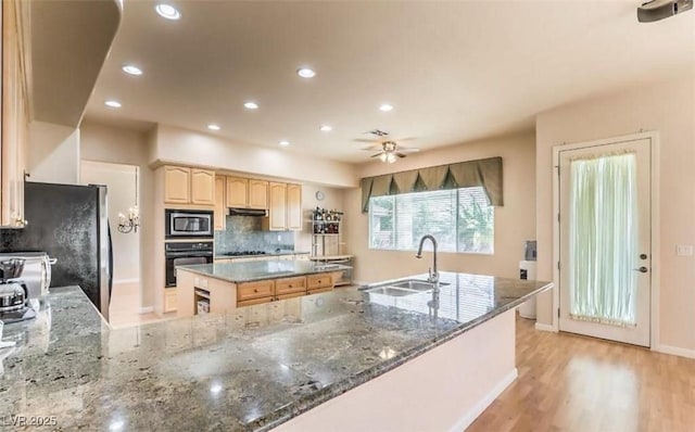 kitchen with appliances with stainless steel finishes, dark stone counters, decorative backsplash, a kitchen island, and sink