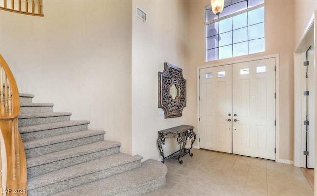 foyer featuring a towering ceiling and light tile patterned floors