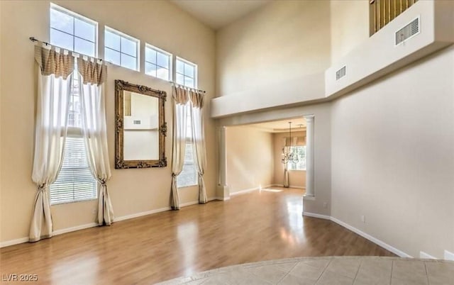 unfurnished room with a high ceiling, an inviting chandelier, and a wealth of natural light