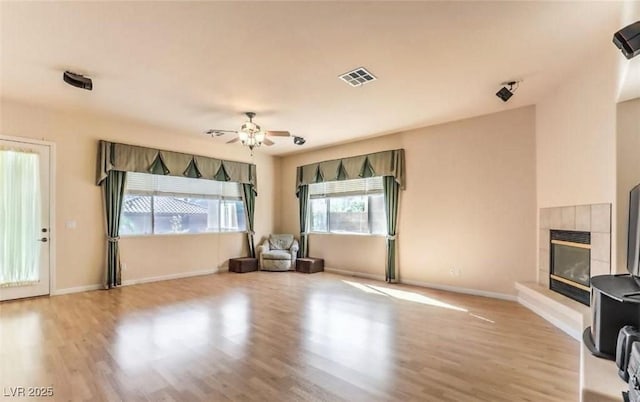 unfurnished living room with a tile fireplace, ceiling fan, and light hardwood / wood-style flooring