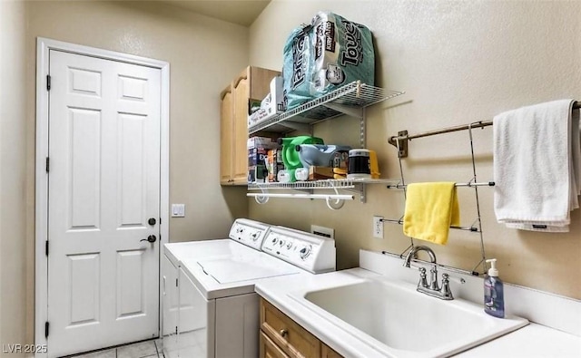 laundry room featuring sink, washing machine and dryer, light tile patterned floors, and cabinets