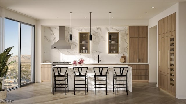 kitchen with light parquet flooring, wall chimney range hood, a kitchen bar, a kitchen island, and decorative backsplash