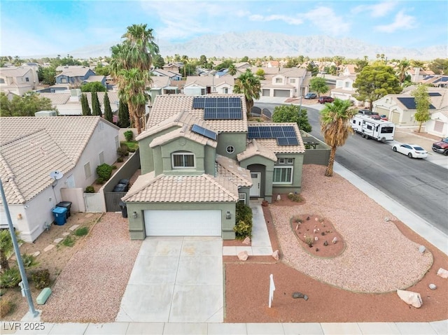 mediterranean / spanish-style house with roof mounted solar panels, fence, a residential view, driveway, and a tiled roof