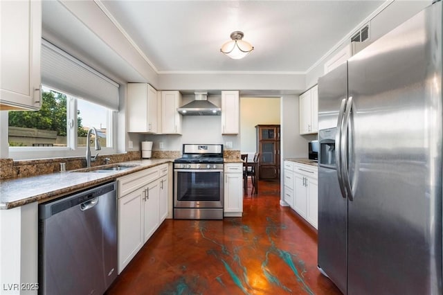 kitchen featuring dark stone countertops, appliances with stainless steel finishes, sink, white cabinetry, and wall chimney range hood