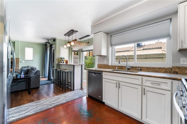 kitchen featuring hanging light fixtures, dark hardwood / wood-style flooring, white cabinets, appliances with stainless steel finishes, and sink