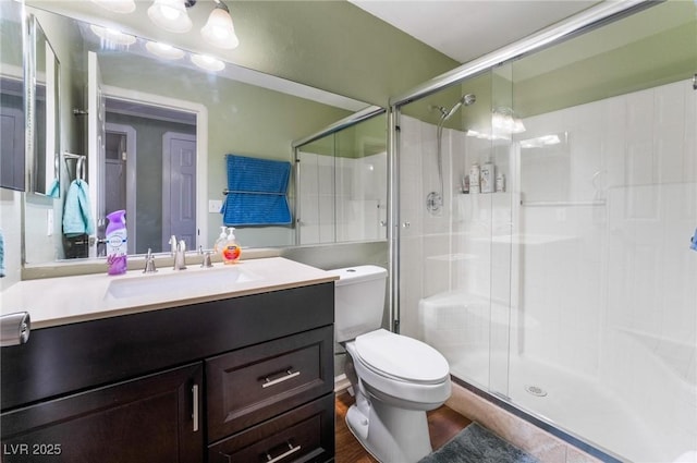 bathroom with toilet, a shower with shower door, and vanity