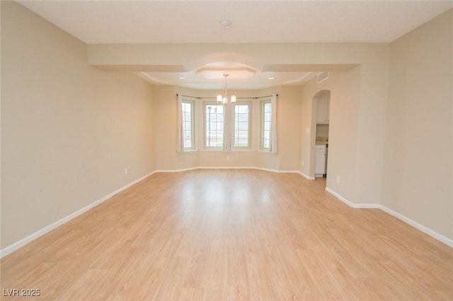 spare room featuring an inviting chandelier and light hardwood / wood-style floors