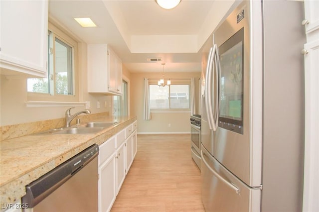 kitchen with sink, decorative light fixtures, white cabinets, light hardwood / wood-style floors, and appliances with stainless steel finishes