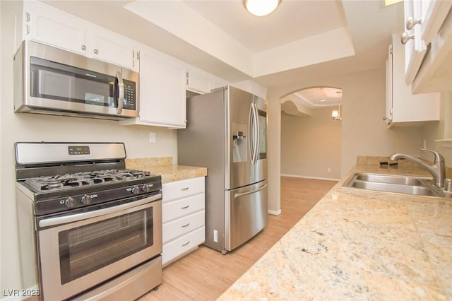 kitchen featuring sink, white cabinetry, a raised ceiling, light hardwood / wood-style flooring, and appliances with stainless steel finishes