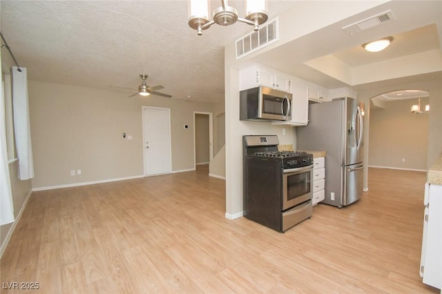 kitchen featuring appliances with stainless steel finishes, light hardwood / wood-style floors, a textured ceiling, white cabinets, and ceiling fan with notable chandelier