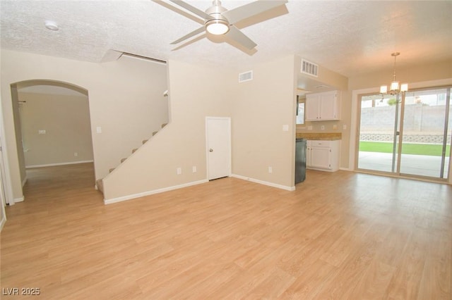 unfurnished living room with ceiling fan with notable chandelier, light wood-type flooring, and a textured ceiling