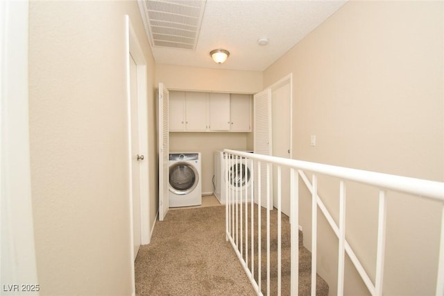 washroom with washer / dryer, a textured ceiling, cabinets, and light carpet