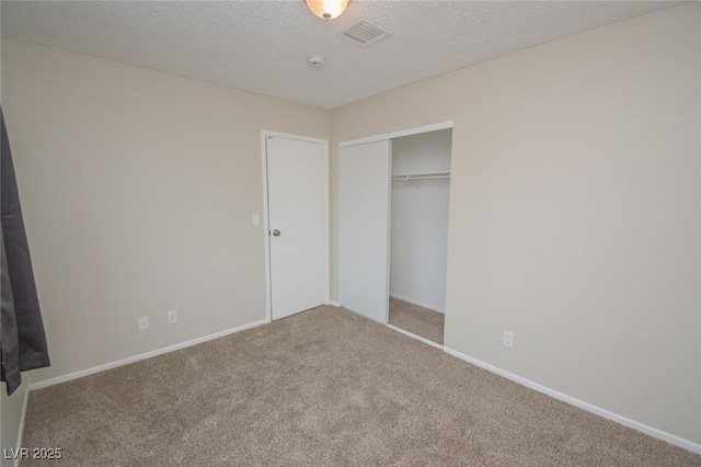 unfurnished bedroom featuring a textured ceiling, a closet, and carpet flooring