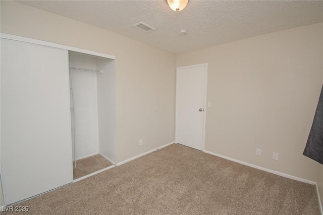 unfurnished bedroom with a textured ceiling, light colored carpet, and a closet