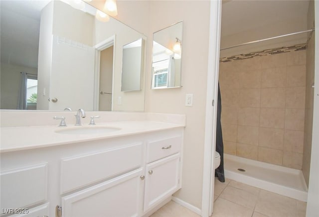 bathroom with a tile shower, toilet, vanity, and tile patterned floors