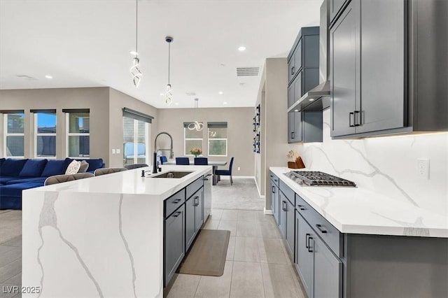 kitchen with sink, stainless steel appliances, decorative light fixtures, a kitchen island with sink, and gray cabinetry