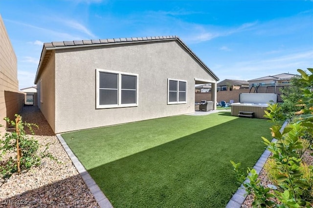 back of house featuring a lawn, a patio area, and a hot tub