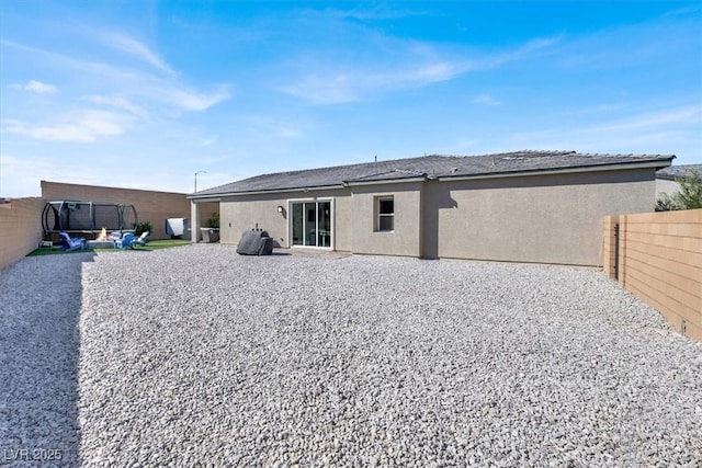 back of house with a patio area and a trampoline