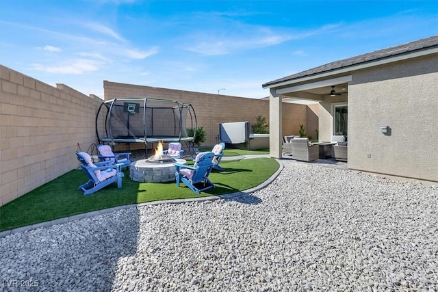 view of yard featuring an outdoor living space with a fire pit, a patio area, and a trampoline