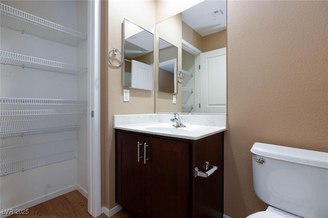 bathroom featuring vanity, hardwood / wood-style floors, and toilet