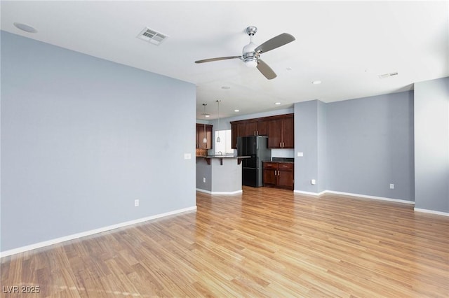 unfurnished living room featuring ceiling fan and light hardwood / wood-style floors