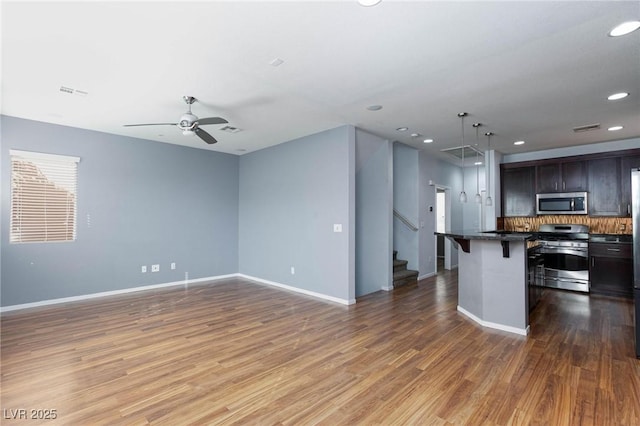 kitchen featuring a breakfast bar area, hanging light fixtures, appliances with stainless steel finishes, dark hardwood / wood-style flooring, and a kitchen island