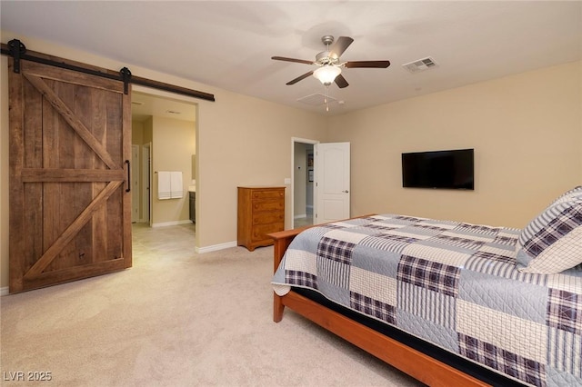 carpeted bedroom with ensuite bathroom, ceiling fan, and a barn door