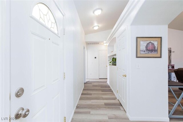 corridor featuring vaulted ceiling and light hardwood / wood-style flooring