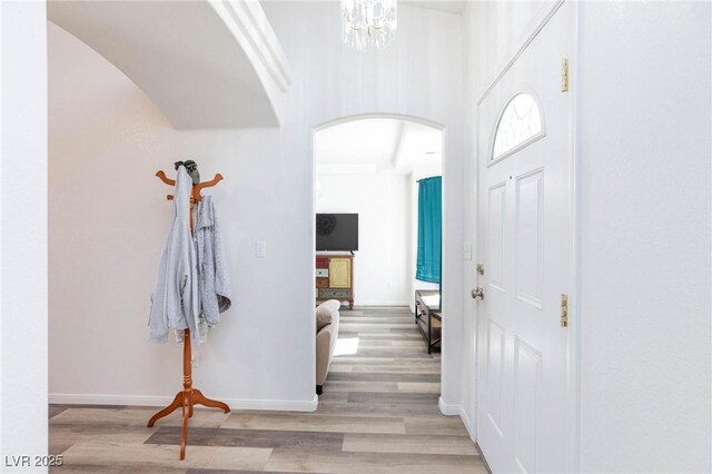 hallway with light wood-type flooring and a notable chandelier