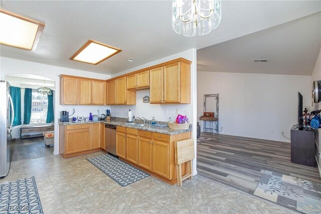 kitchen featuring an inviting chandelier, stainless steel appliances, light stone counters, and sink