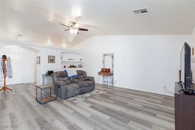 living room featuring vaulted ceiling, ceiling fan, light hardwood / wood-style flooring, and built in shelves