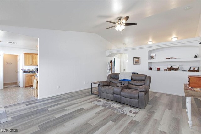 living room featuring lofted ceiling, light wood-type flooring, built in features, and ceiling fan