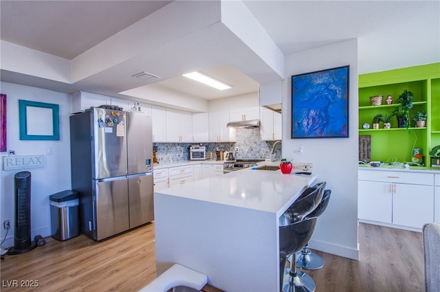 kitchen featuring stainless steel appliances, sink, white cabinetry, kitchen peninsula, and backsplash