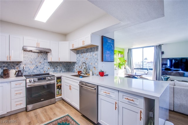 kitchen with kitchen peninsula, white cabinets, appliances with stainless steel finishes, and sink