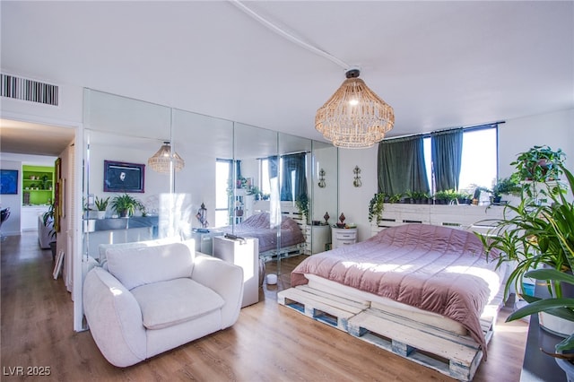 bedroom with an inviting chandelier and wood-type flooring