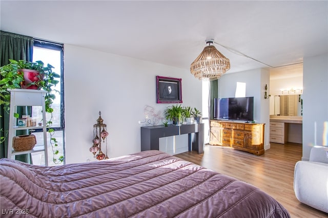 bedroom featuring ensuite bath, a notable chandelier, and hardwood / wood-style flooring