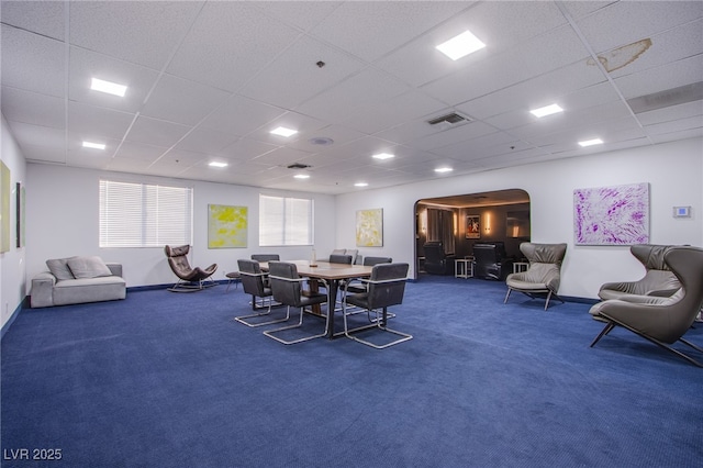 dining space with dark colored carpet and a drop ceiling