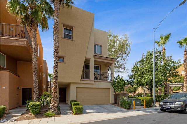 view of front of home with concrete driveway, a balcony, a garage, and stucco siding