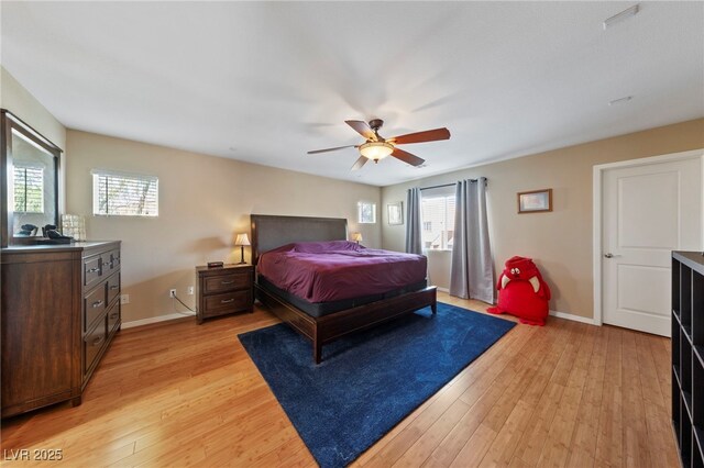 bedroom featuring ceiling fan, light wood-type flooring, and multiple windows