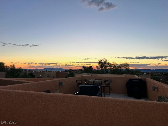 patio terrace at dusk featuring a balcony and a mountain view