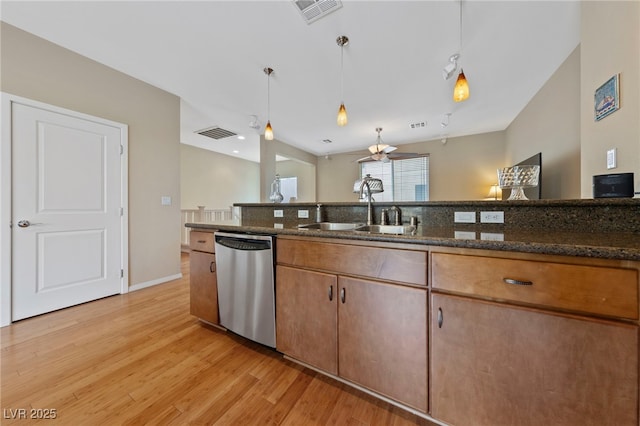 kitchen with dark stone countertops, dishwasher, pendant lighting, and sink