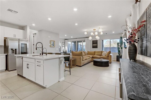 kitchen with a kitchen island with sink, appliances with stainless steel finishes, light tile patterned floors, sink, and white cabinetry