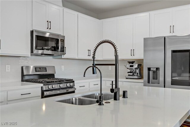 kitchen with white cabinets, stainless steel appliances, and backsplash