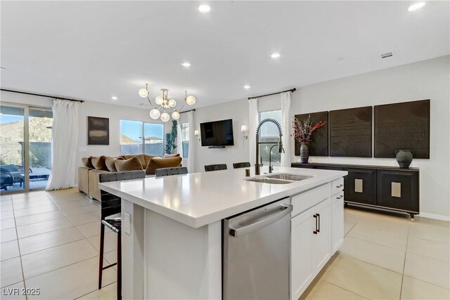 kitchen with sink, white cabinetry, dishwasher, light tile patterned floors, and a kitchen island with sink