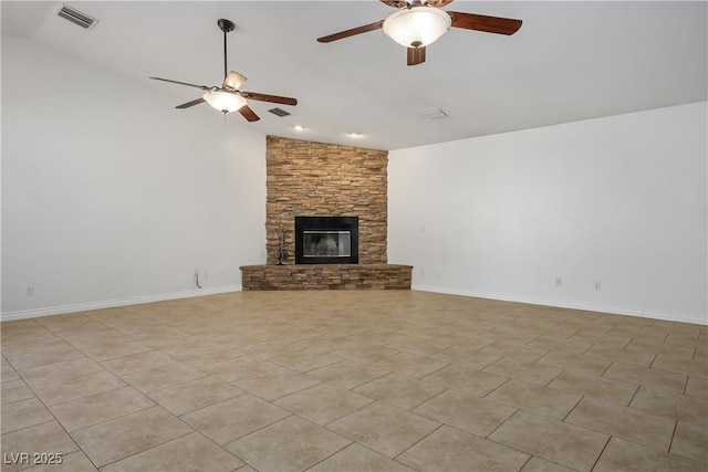 unfurnished living room with ceiling fan, vaulted ceiling, light tile patterned floors, and a stone fireplace