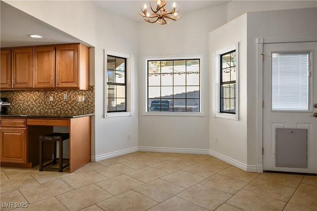 kitchen with decorative light fixtures, light tile patterned flooring, backsplash, and a notable chandelier